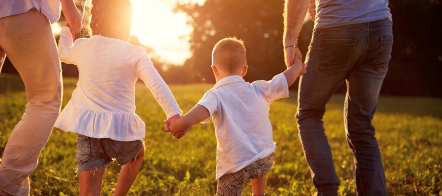 family with kids kids walking in sunset with parents holding hand