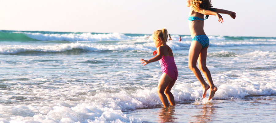 Summer Sun Safety girls jumping on the beach having fun